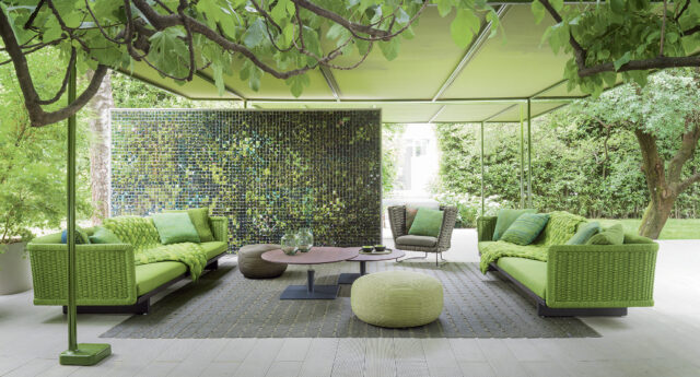 Moderne Outdoor-Lounge mit grünen Sofas, Sesseln und Hockern unter einem grünen Baldachin auf einer gefliesten Terrasse, die elegantes, vom luxemburgischen Stil inspiriertes Gardendesign zeigt.
