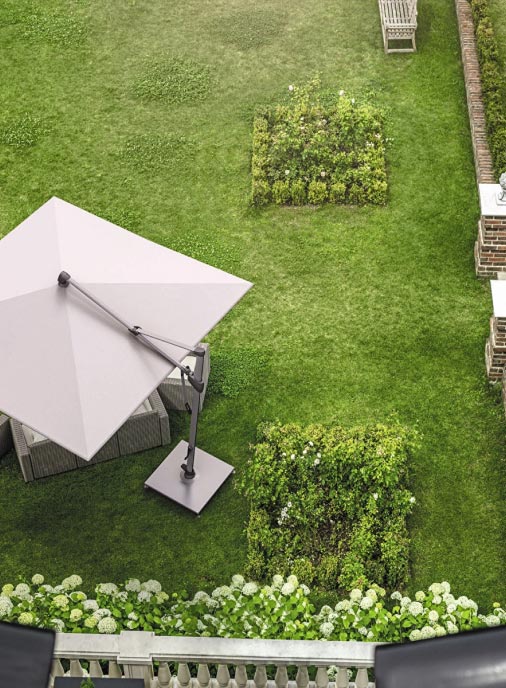 Luftaufnahme eines grünen Gartens mit einem quadratischen weißen Terrassenschirm, zwei kleinen rechteckigen Blumenbeeten, einer weißen Bank und einem weißen Lattenzaun - ein Beispiel für elegantes Gardendesign und fachmännisches Handwerk.