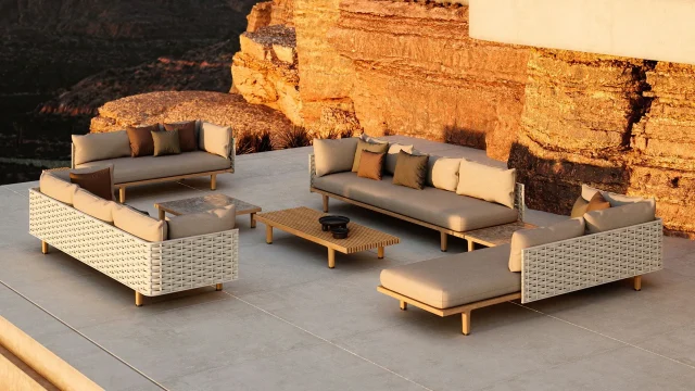Eine Terrasse mit modernen beigen und weißen Gartenmöbeln, einem niedrigen Couchtisch aus Holz und einer felsigen Wüstenklippe im Hintergrund, die in warmes Sonnenlicht getaucht ist - die perfekte Inspiration für Garten- und Landschaftsbau in Deutschland und Luxemburg.