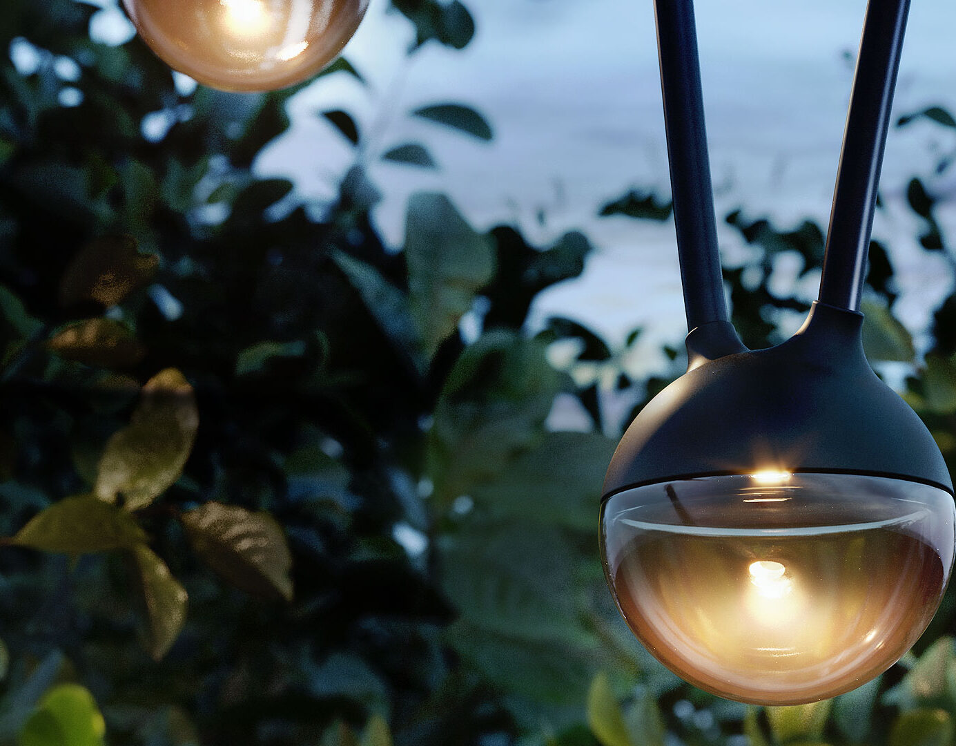 Nahaufnahme einer modernen Hängelampe für den Außenbereich, die in der Abenddämmerung warm leuchtet und die Atmosphäre verbessert - perfekt für Garten- und Landschaftsbauprojekte in Luxemburg und Deutschland, mit grünen Blättern und einem verschwommenen blauen Himmel im Hintergrund.