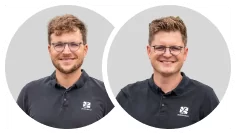 Zwei Männer mit kurzen, hellbraunen Haaren und Brille, beide tragen schwarze Kragenhemden mit weißem Burelbach-Logo, lächeln in die Kamera vor einem schlichten hellgrauen Hintergrund. Experten für Garten- und Landschaftsbau in Luxemburg und Deutschland.